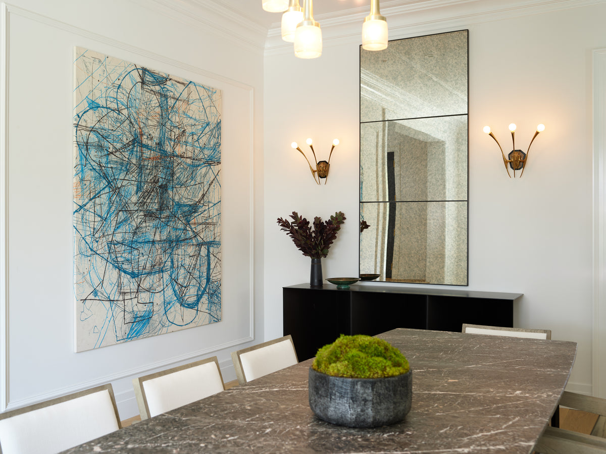 Marble dining table below brass sconces and a blue abstract canvas, Martin & Brockett Beverly Hills