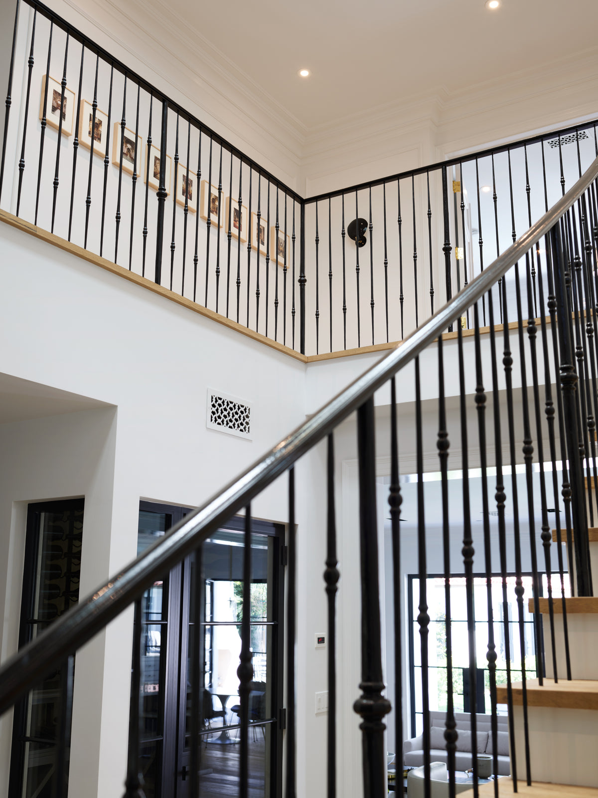 Black iron balustrade and oak handrail rising through the stair hall, Martin & Brockett Beverly Hills