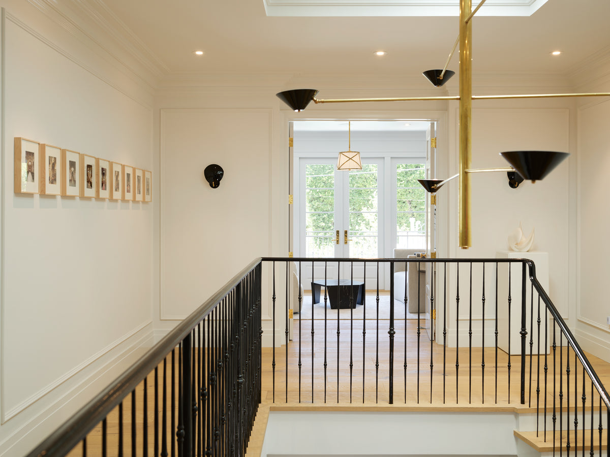 Brass chandelier above a gallery of framed prints on the landing, Martin & Brockett Beverly Hills