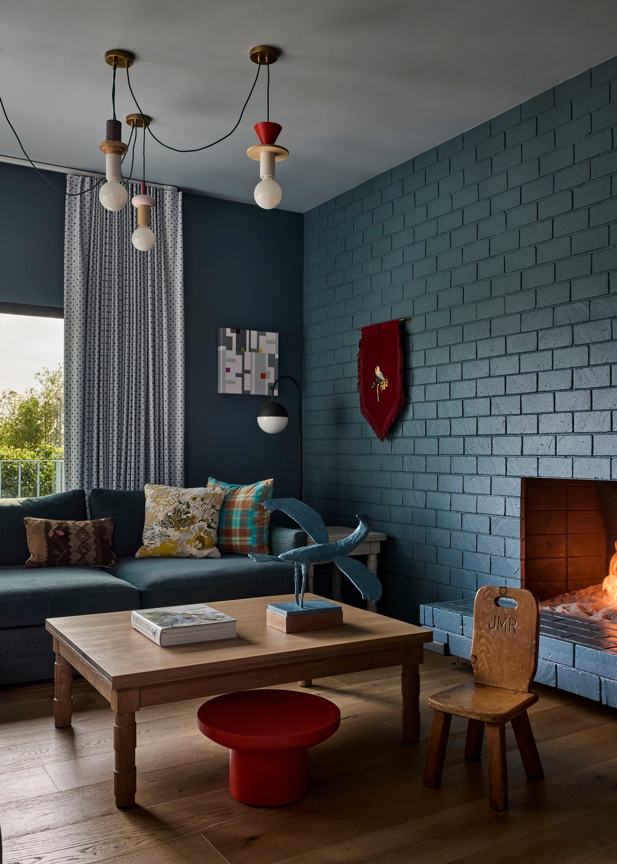Painted brick fireplace wall beside a teal sofa and red side table, Martin & Brockett Canyon den