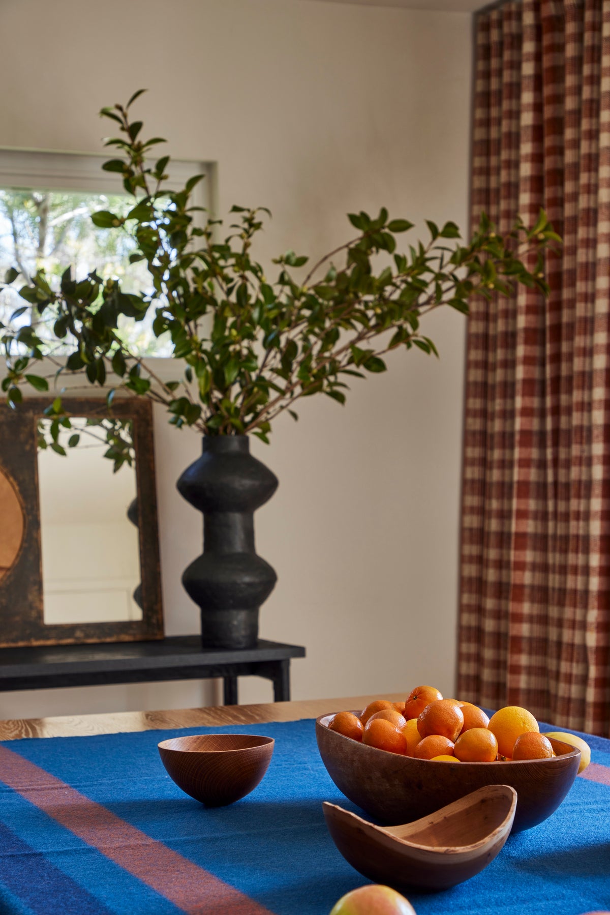 Branches in a black vase beside bowls of citrus on the dining table, Martin & Brockett Eastside Hills