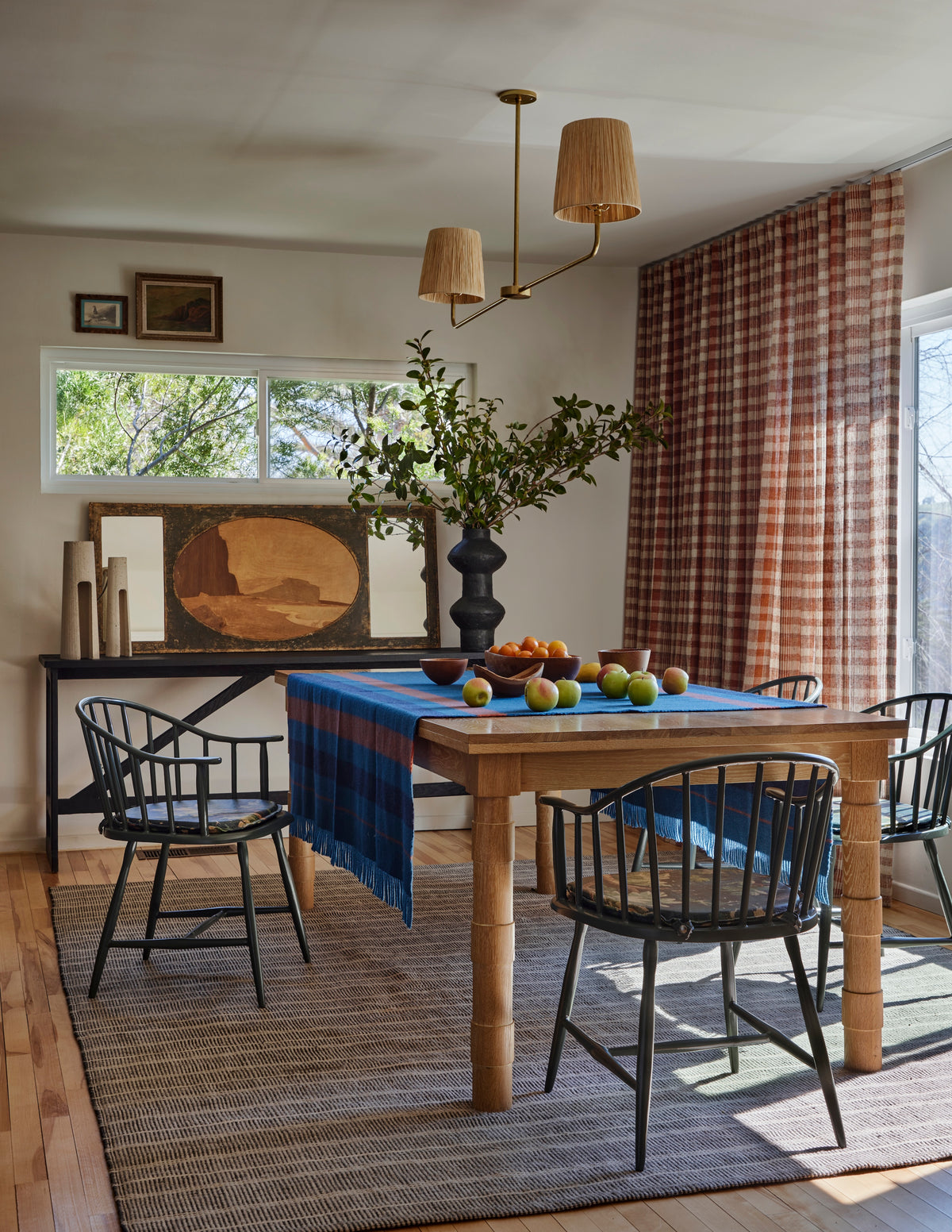 Oak dining table and black spindle chairs below a rattan chandelier, Martin & Brockett Eastside Hills