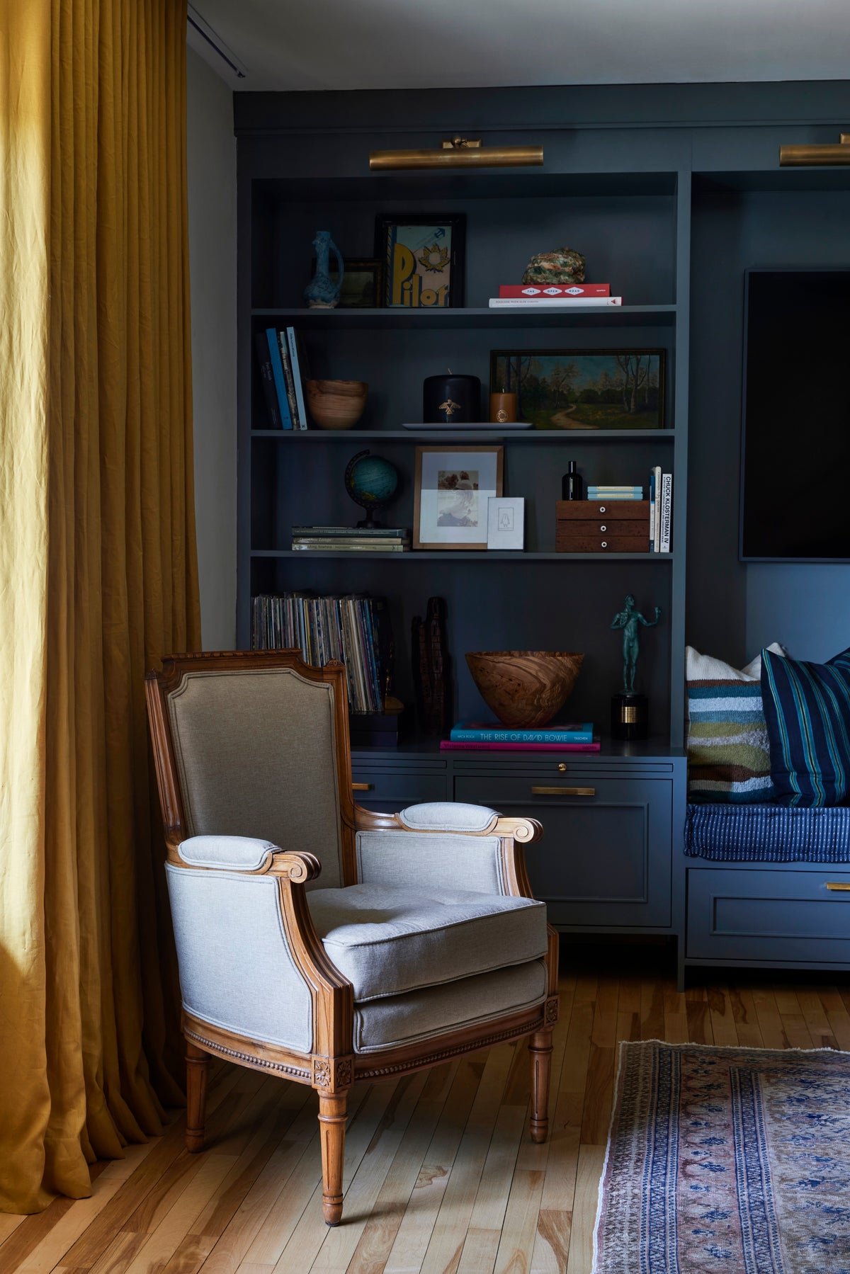 Antique armchair against ochre drapery and blue built-ins, Martin & Brockett Eastside Hills living room