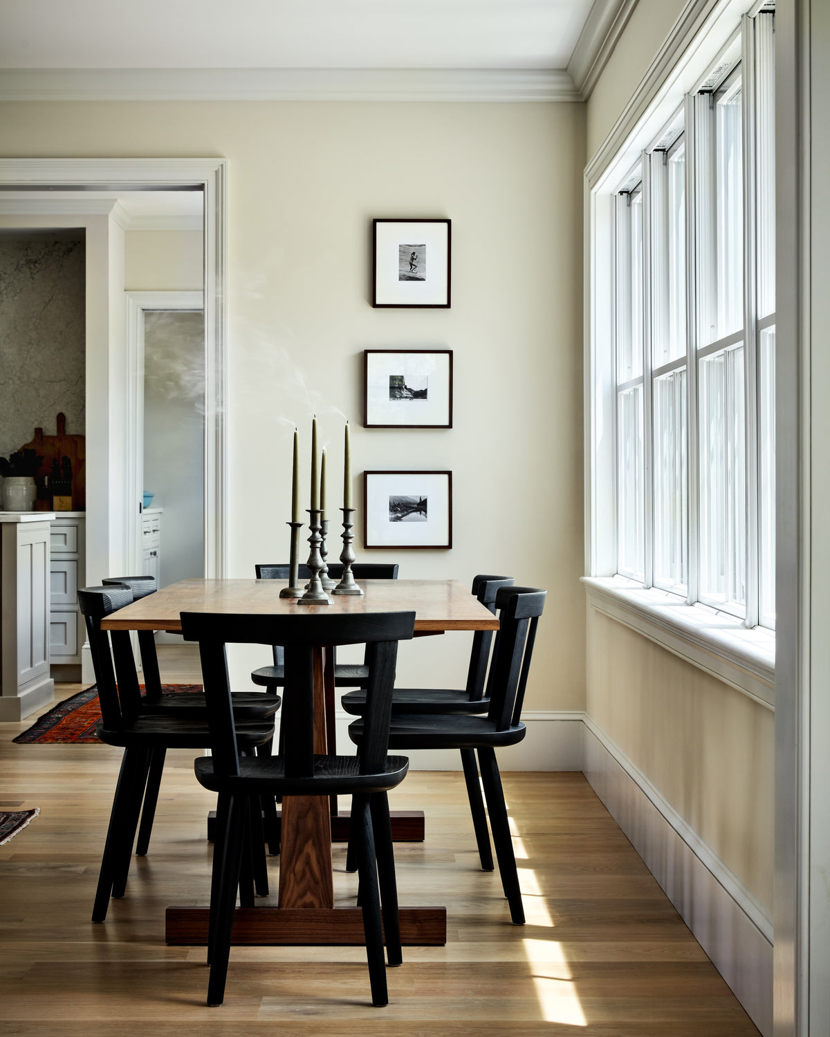 Black pedestal dining table and Windsor chairs beside a wall of windows, Martin & Brockett Hudson Valley