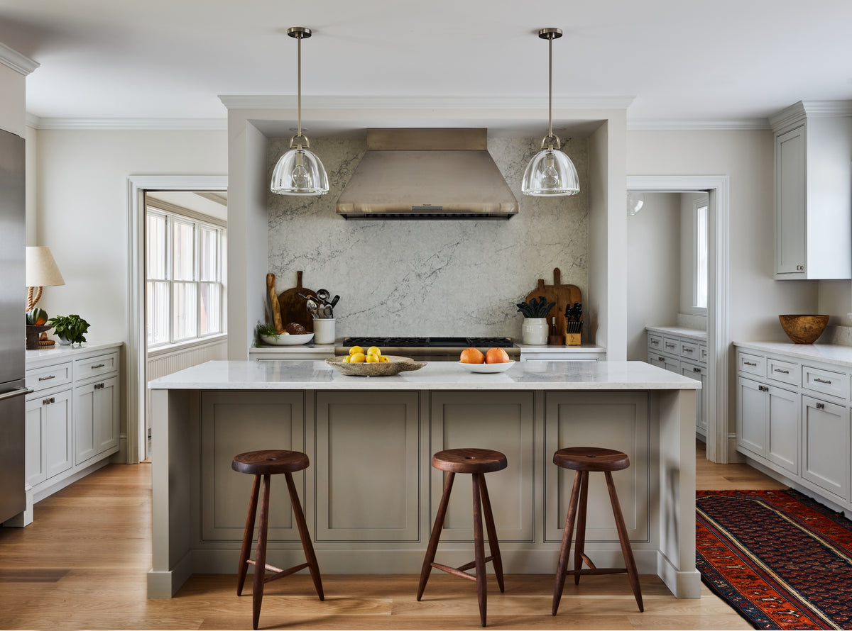 Marble slab backsplash and plaster hood above an island with wood stools, Martin & Brockett Hudson Valley