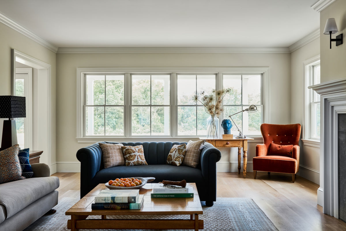 Navy chesterfield sofa and antique writing table under a wall of windows, Martin & Brockett Hudson Valley
