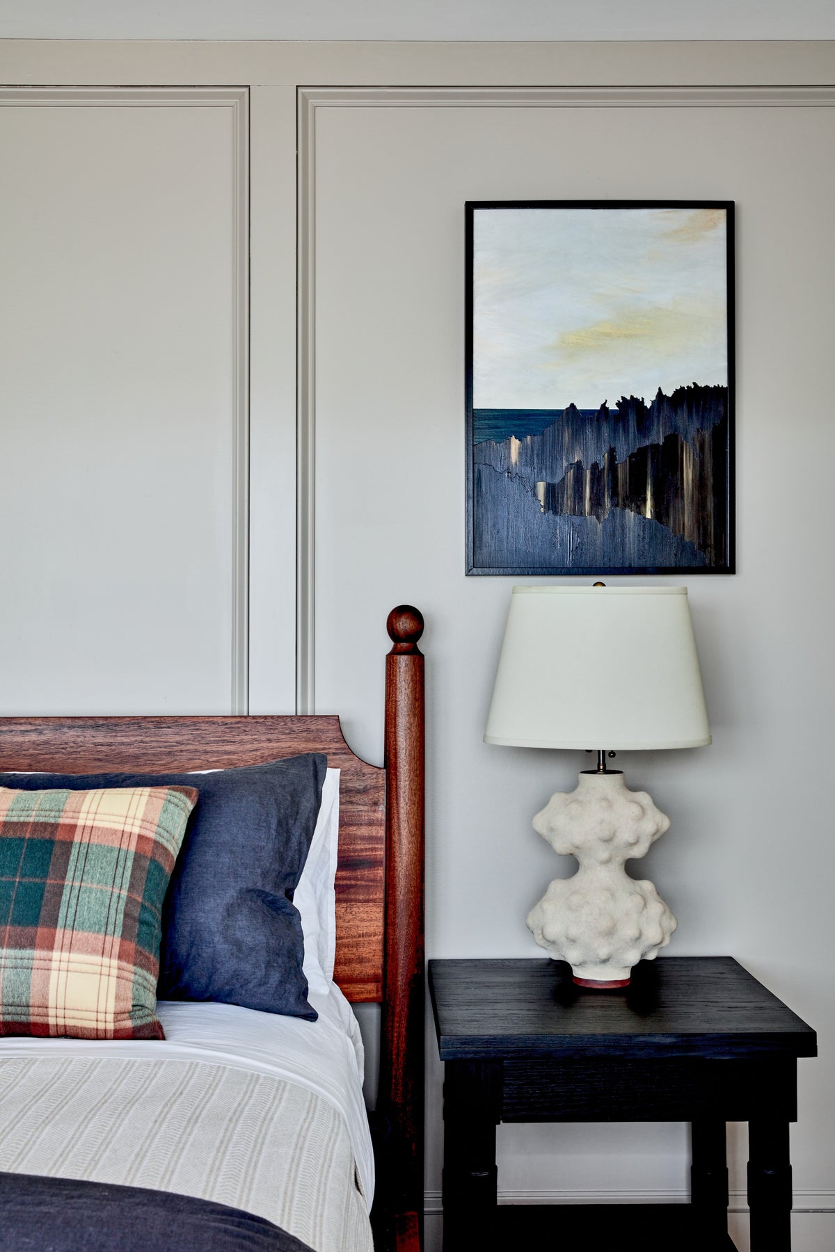 Sculptural lamp and framed landscape beside the carved bedpost, Martin & Brockett Hudson Valley bedroom