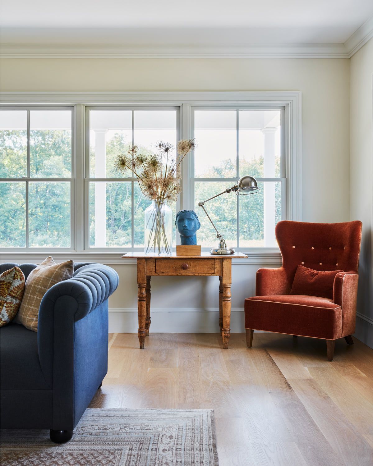 Antique writing desk and rust velvet wingback beside a navy sofa, Martin & Brockett Hudson Valley