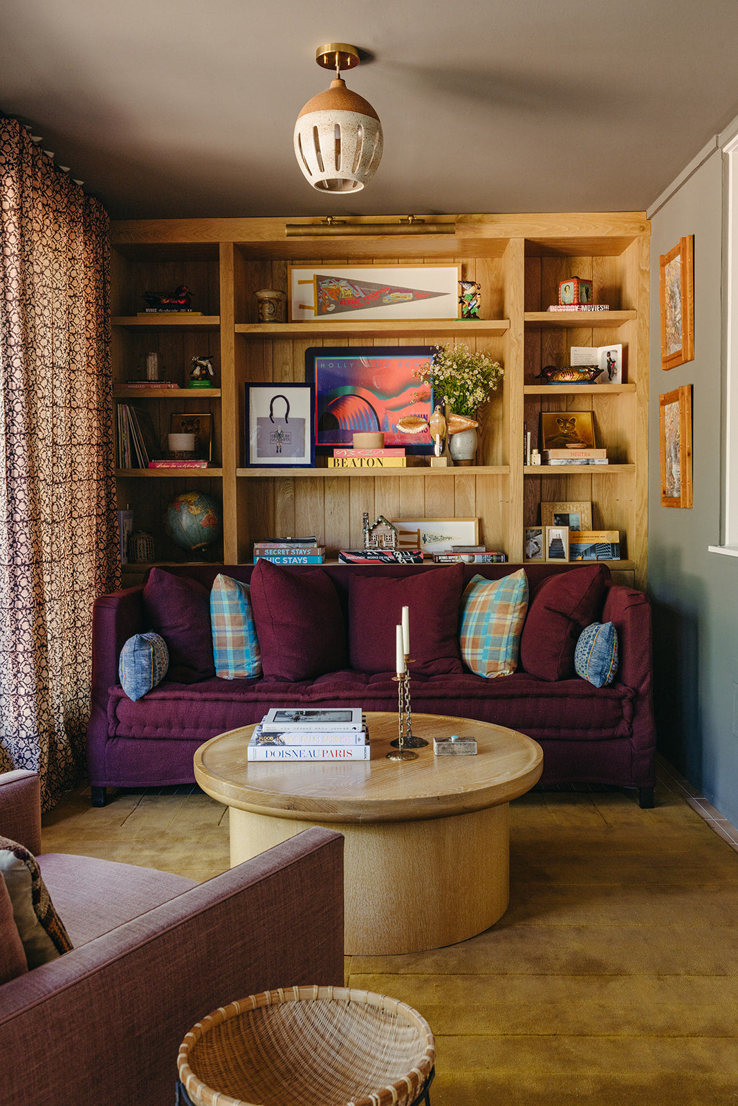 Oak built-in bookshelves flanking a burgundy velvet sofa in the den of Martin & Brockett's Pasadena project