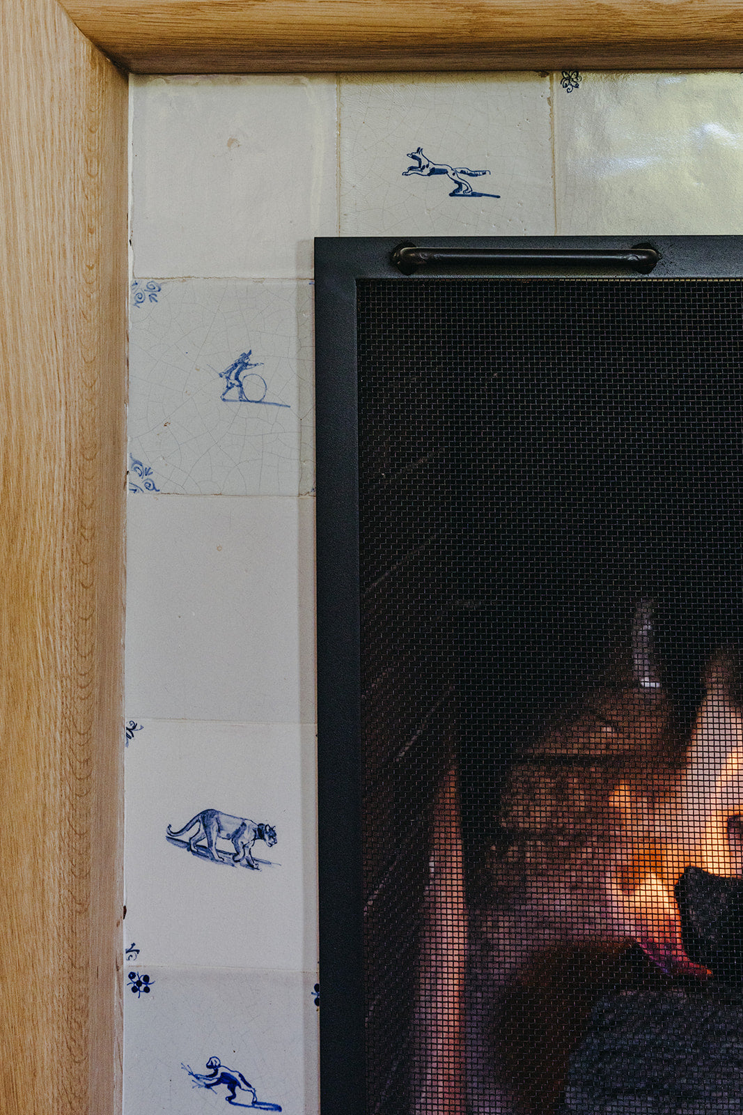 Hand-painted blue and white Delft tile surrounding the lit fireplace, Martin & Brockett Pasadena