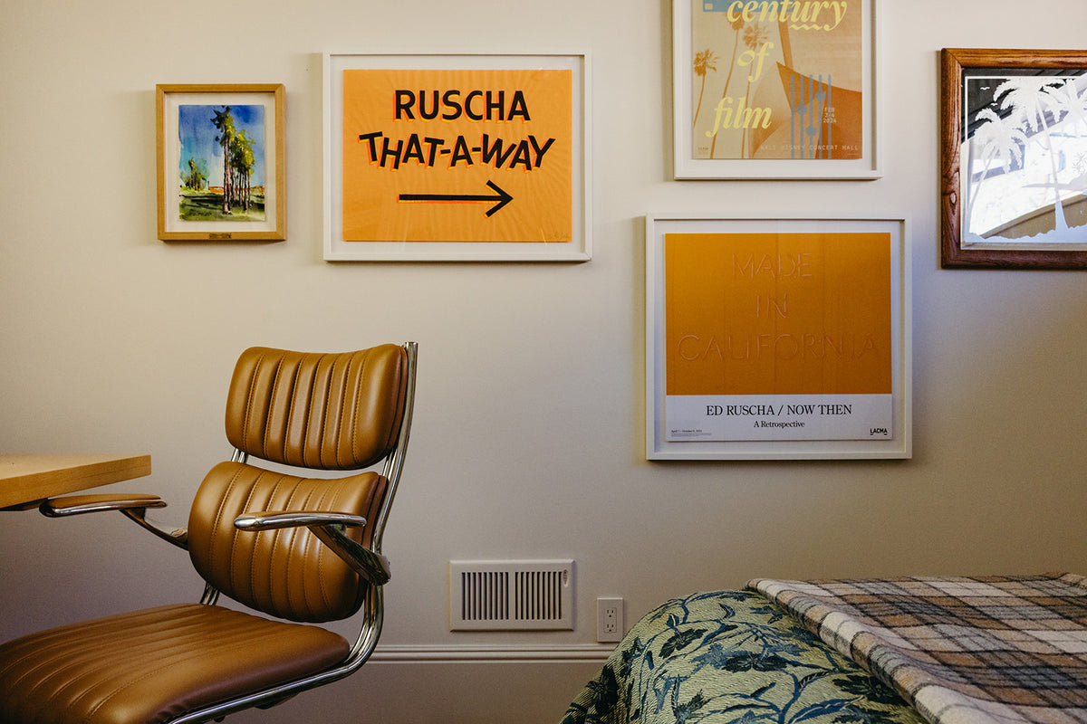 Gallery wall of prints above a tan leather chair, Martin & Brockett Pasadena guest bedroom