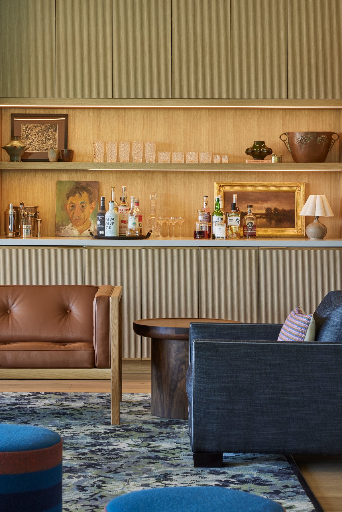 Fluted oak bar cabinetry seen past a leather chair and navy sofa, Martin & Brockett San Rafael