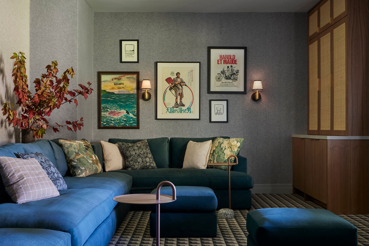 Blue sectional below a gallery wall of vintage posters, Martin & Brockett San Rafael den