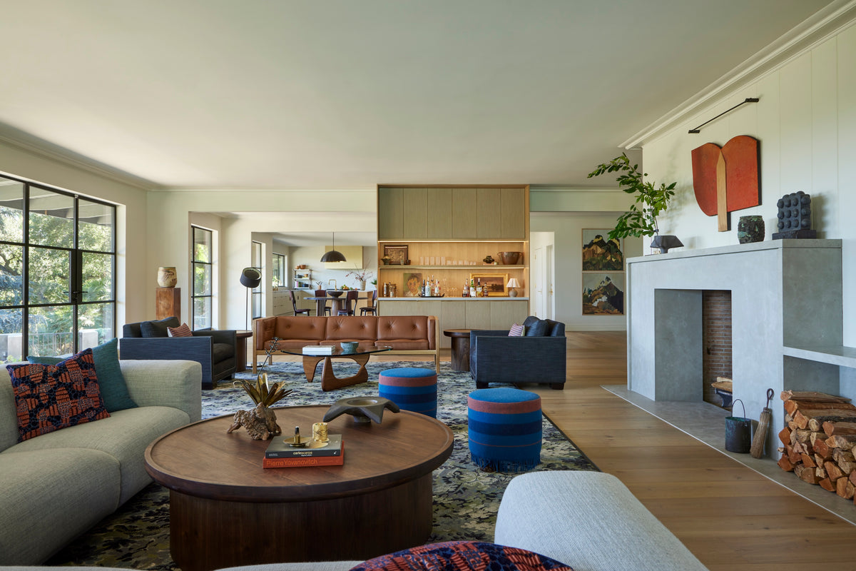 Stone fireplace between curved sofas and blue poufs, Martin & Brockett San Rafael great room