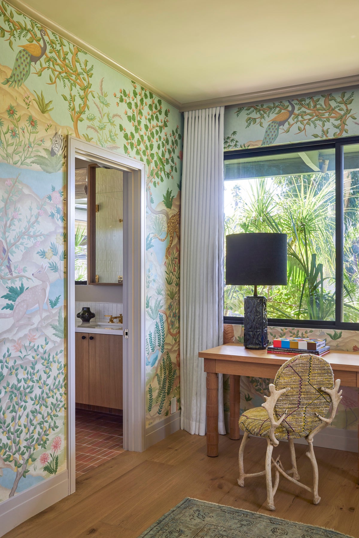 Scenic botanical wallpaper behind a desk and rattan chair, Martin & Brockett San Rafael guest bedroom