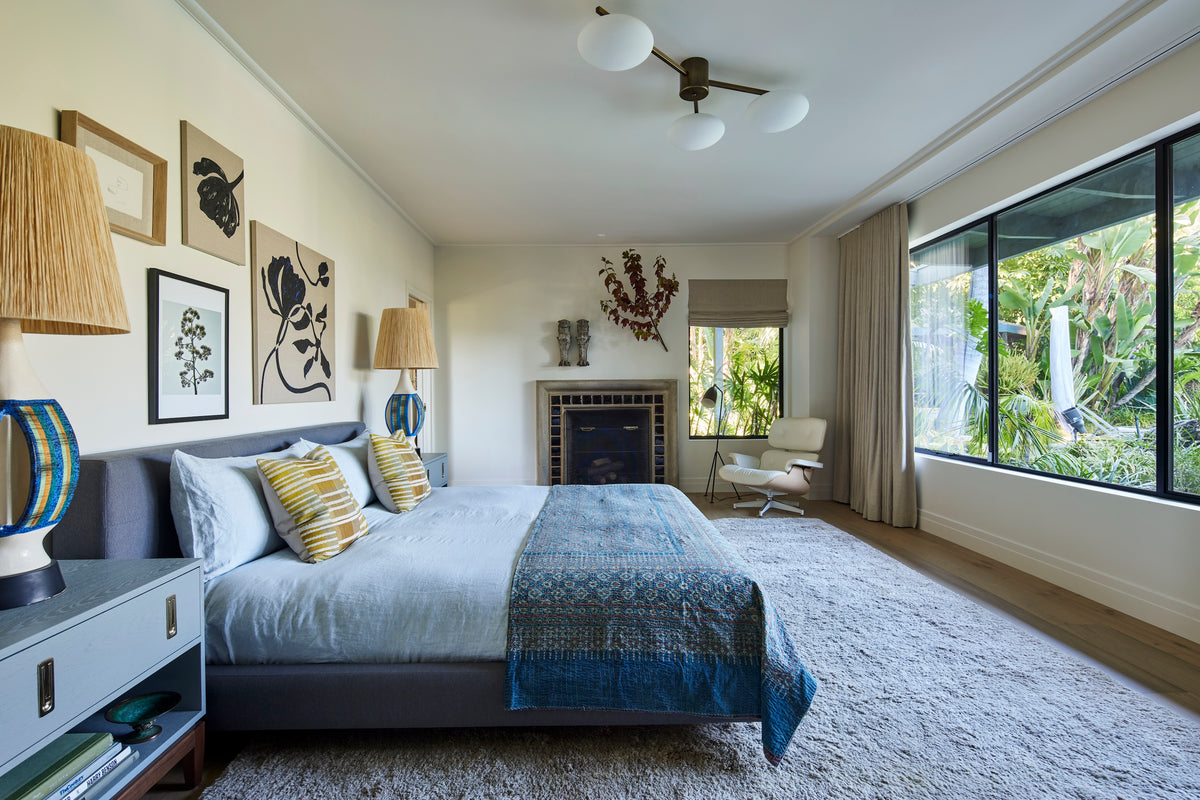 Upholstered bed and indigo throw below a gallery wall, Martin & Brockett San Rafael primary bedroom