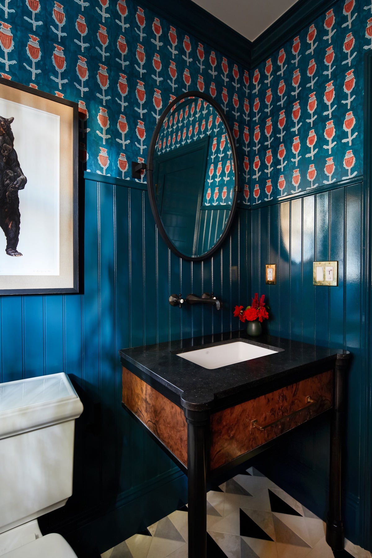 Burl vanity below an oval mirror in the Studio City powder room by Martin & Brockett