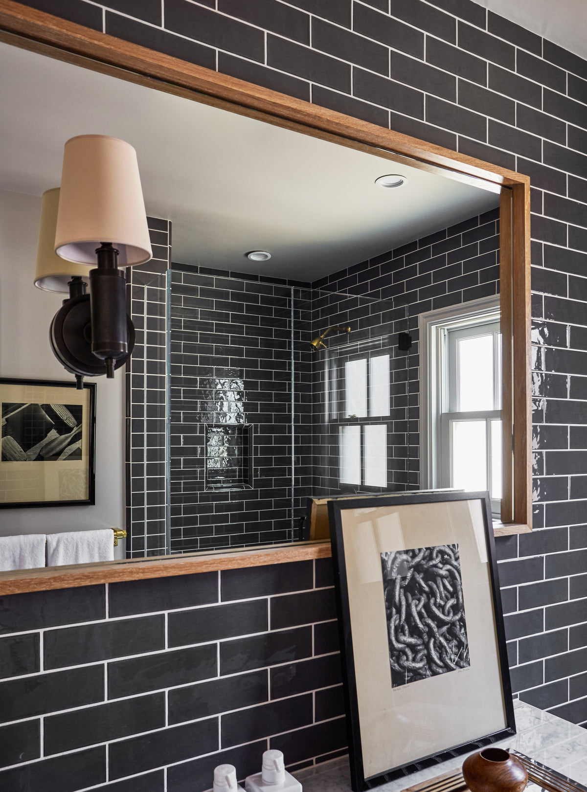 Wood-framed mirror and sconce against black subway tile, Martin & Brockett Toluca Lake bathroom