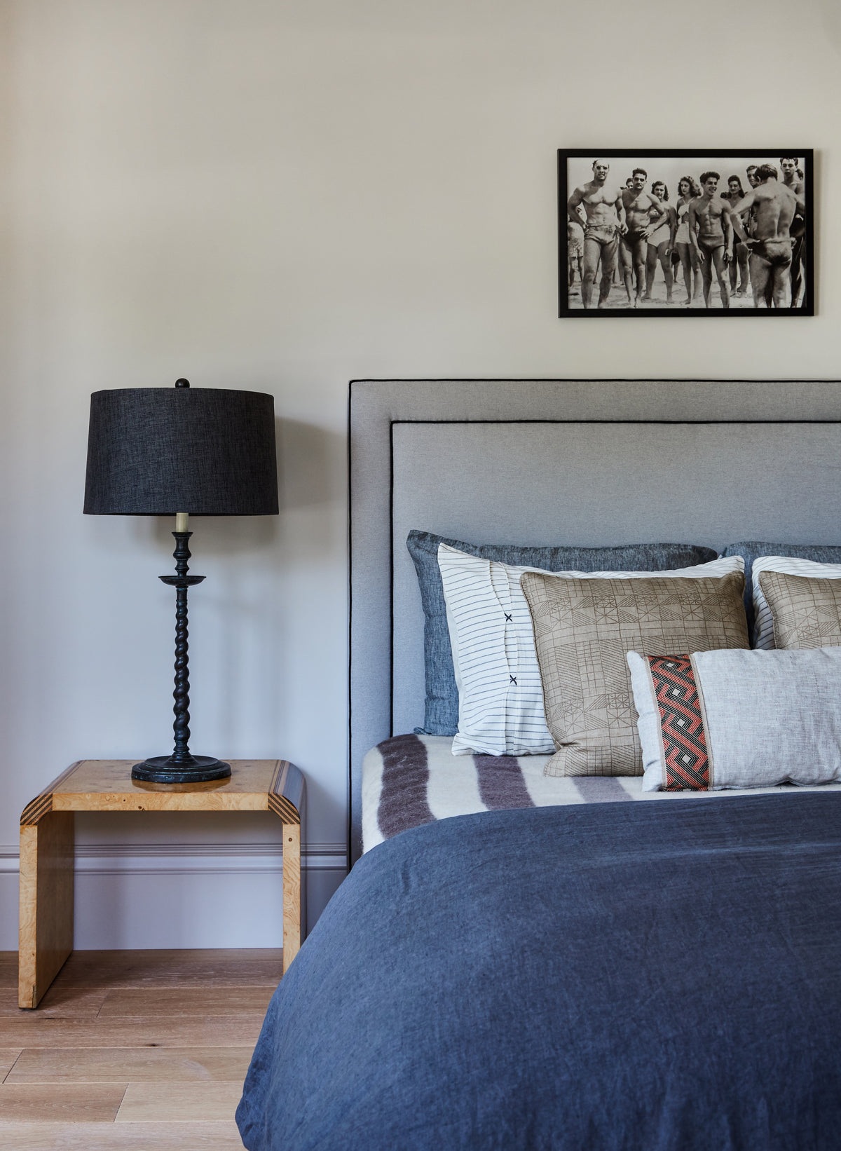 Upholstered headboard and navy bedding beside a wood nightstand, Martin & Brockett Toluca Lake
