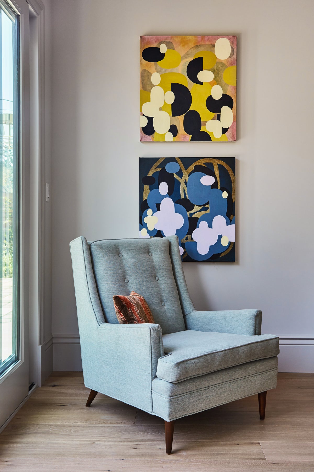 Pale blue wingback chair below paired abstract paintings, Martin & Brockett Toluca Lake