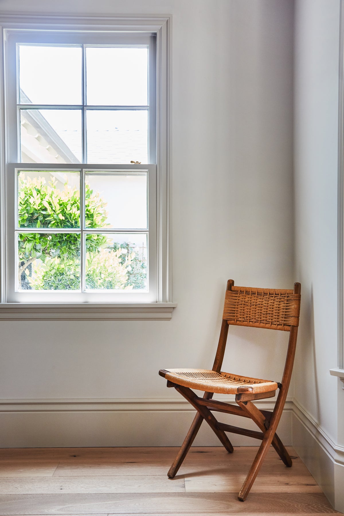 Woven folding chair in a sunlit bedroom corner, Martin & Brockett Toluca Lake