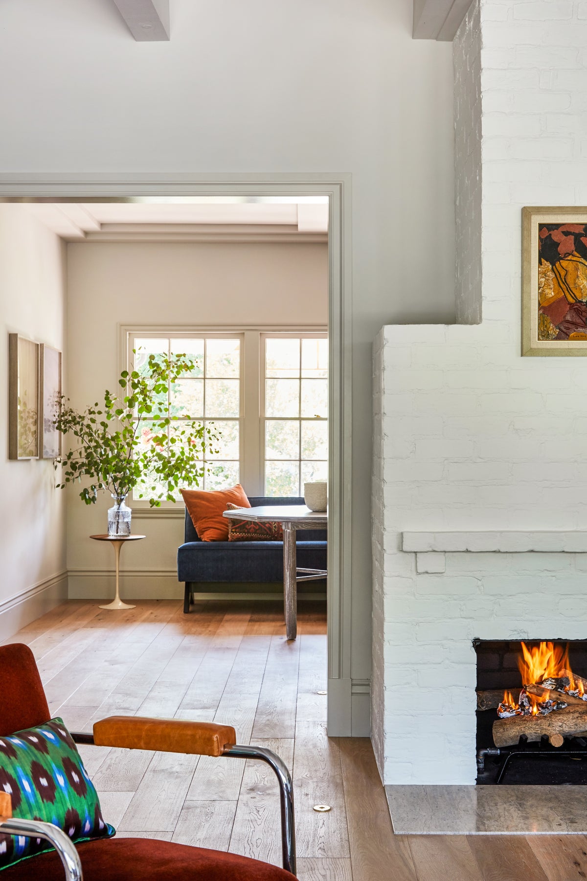Lit fireplace beside a rust leather chair, Martin & Brockett Toluca Lake living room
