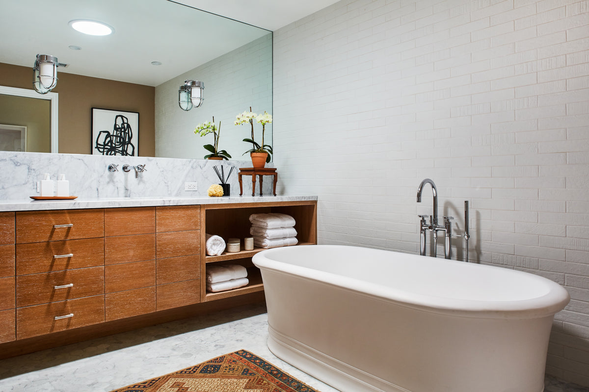 Freestanding tub on an antique runner against white brick, Martin & Brockett Toluca Lake