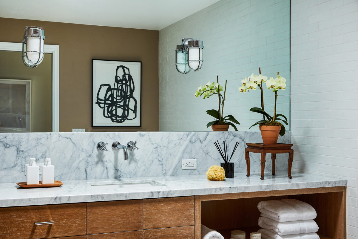 Orchids and twin sconces above the marble vanity, Martin & Brockett Toluca Lake primary bathroom
